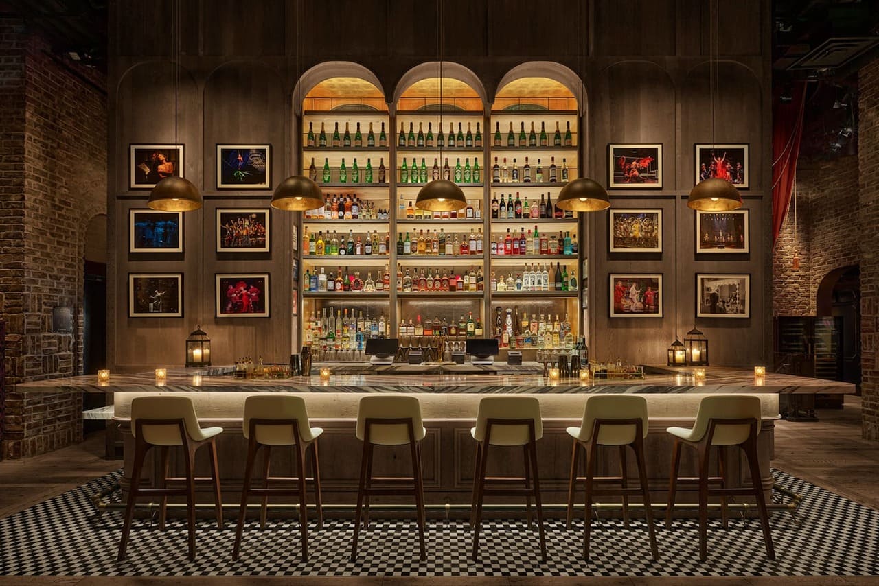 Elegant bar interior with checkered flooring and illuminated bottle shelves