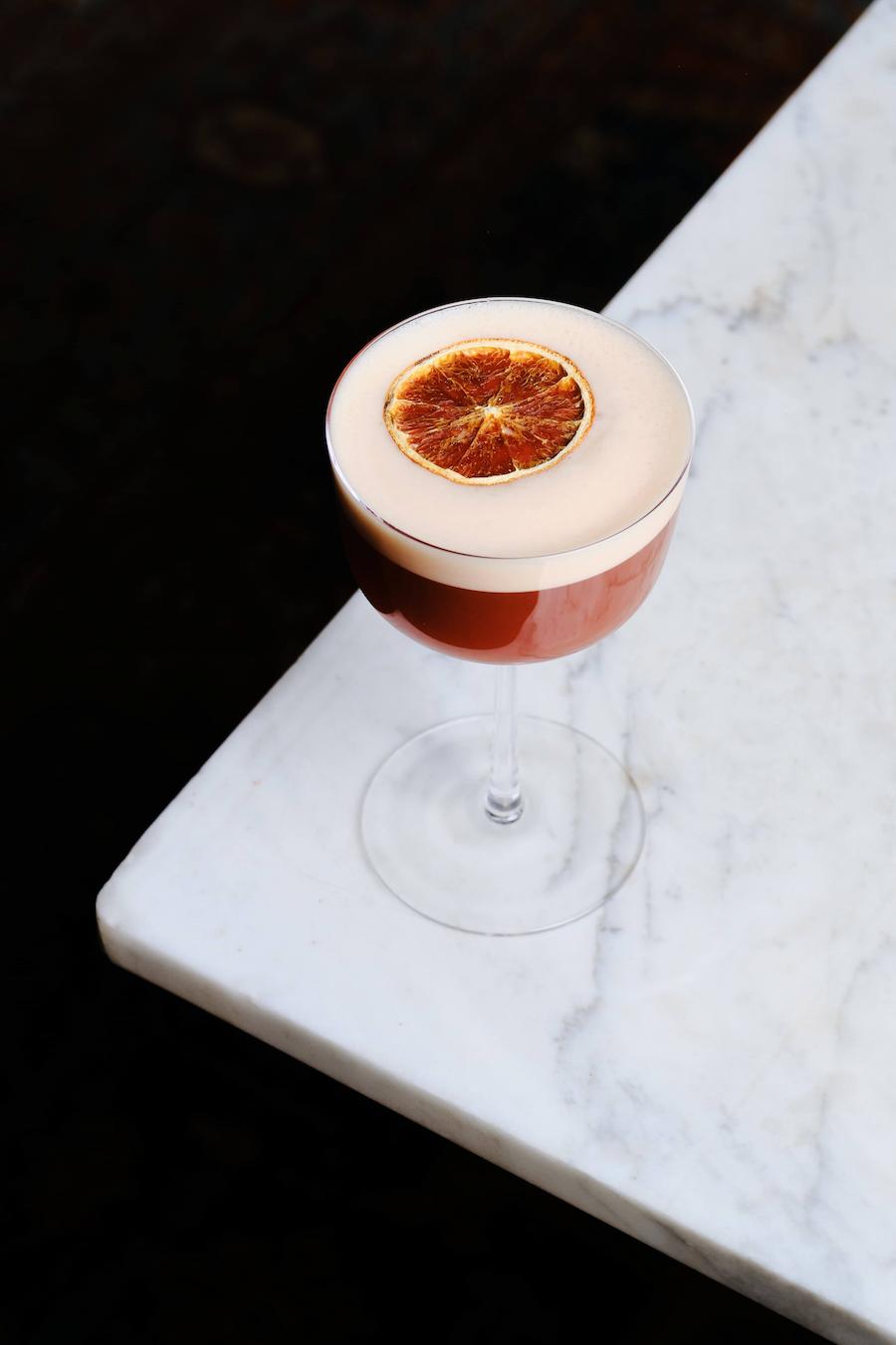 Rosevale pink cocktail with citrus garnish on marble bar table